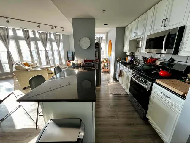 a kitchen with stainless steel appliances granite countertop a stove top oven a sink dishwasher and white cabinets with wooden floor