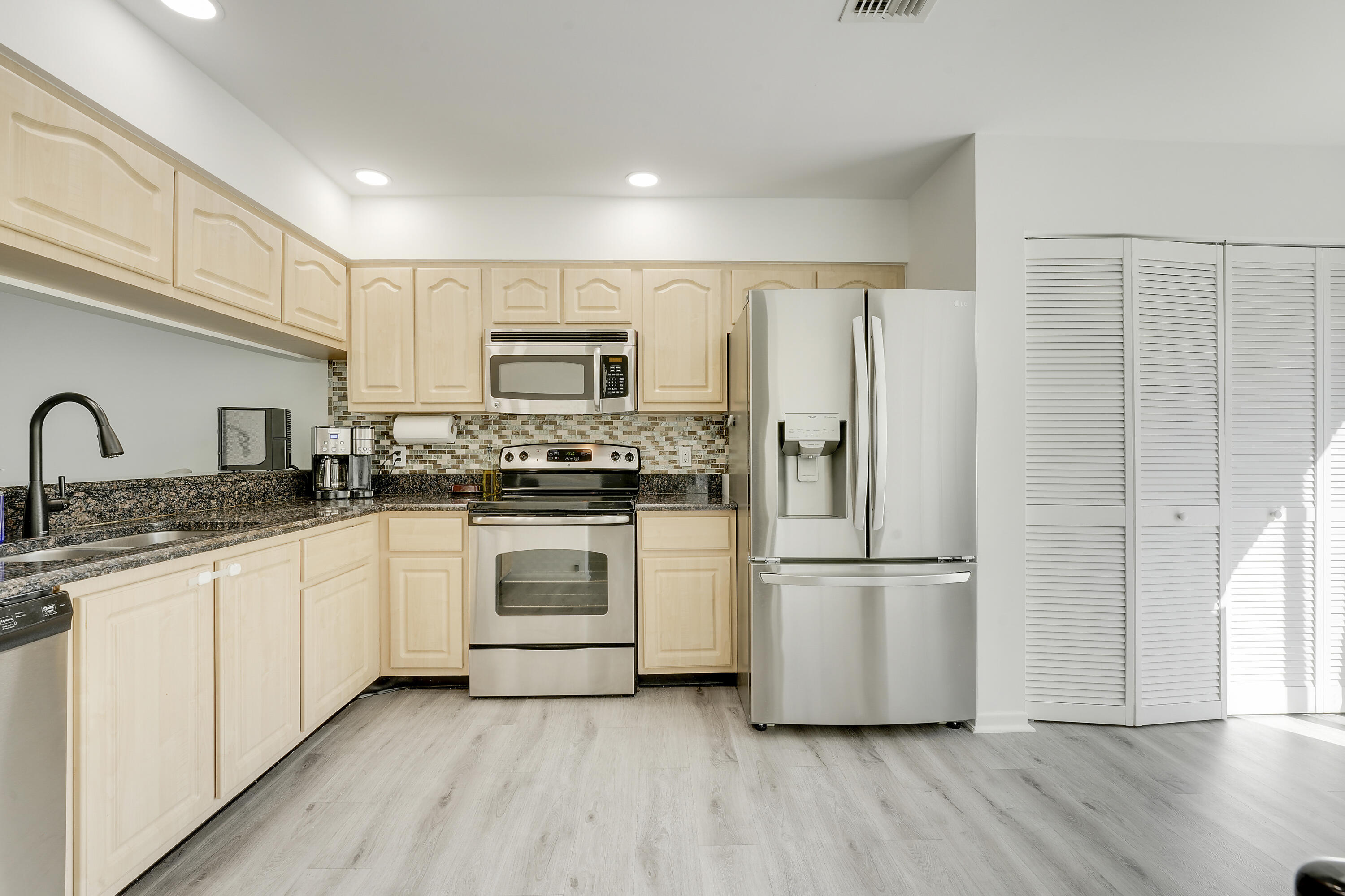 6263 Riverwalk Lane, Unit 2 Jupiter, FL 33458 - Photo 13 of 44 a kitchen with white cabinets stainless steel appliances and a refrigerator