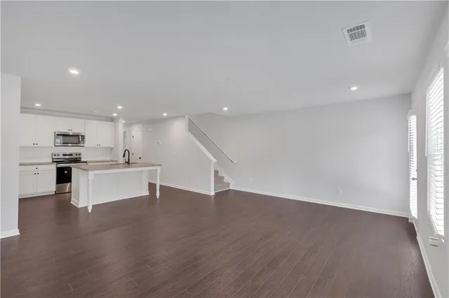 a view of kitchen with kitchen island wooden floor center island and stainless steel appliances