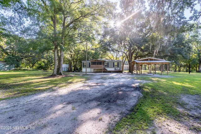 a view of a house with big yard and large trees
