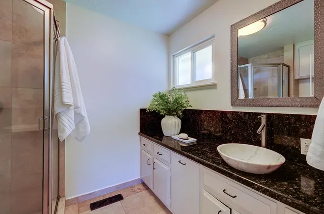 a bathroom with a granite countertop sink and a mirror