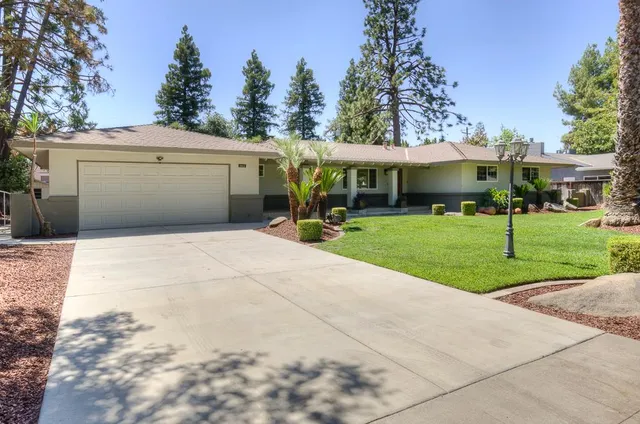 a view of a white house with a yard and trees