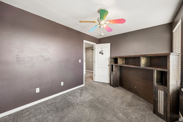 3215 West 450 North West Point, UT 84015 - Photo 22 of 40 Carpeted room with dark gray walls and a ceiling fan with colorful blades