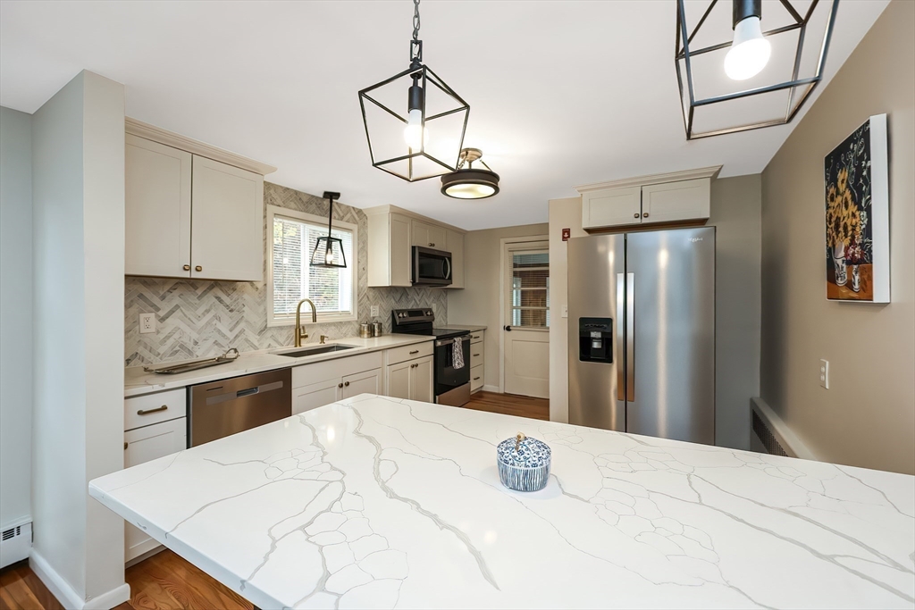 35 Deerfield Road Sharon, MA 02067 - Photo 3 of 31 a kitchen with stainless steel appliances kitchen island granite countertop a refrigerator a stove top oven a sink dishwasher with a dining table and chairs