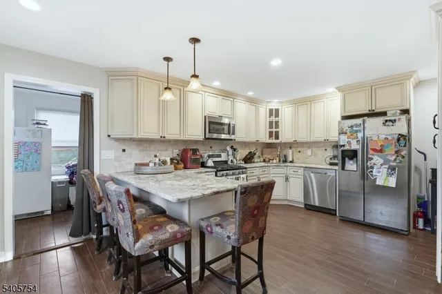 a kitchen with stainless steel appliances granite countertop a stove top oven a sink a dining table and chairs with wooden floor