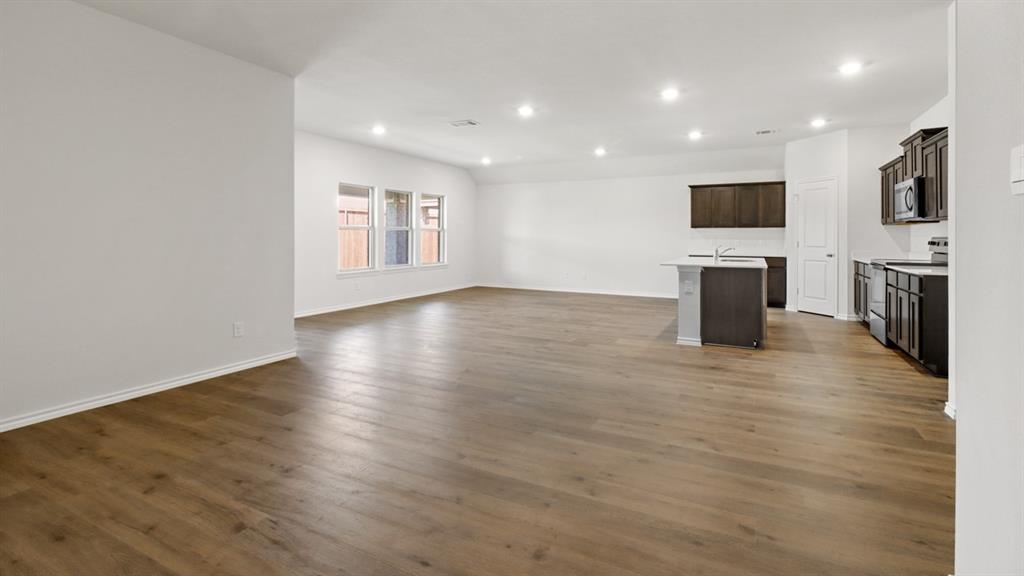 1923 Reveille Way Terrell, TX 75160 - Photo 12 of 33 Expansive open-concept space featuring wood-finish flooring, recessed lighting, and a kitchen island with sink