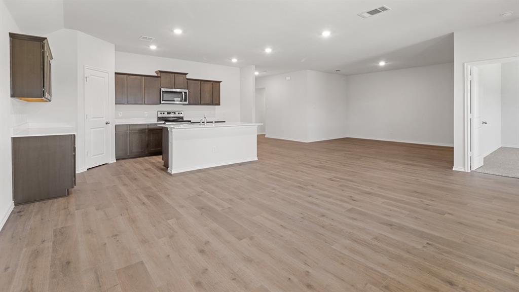 1923 Reveille Way Terrell, TX 75160 - Photo 15 of 33 Open-concept living area featuring wood-finish flooring, recessed lighting, and a kitchen island with a double basin sink