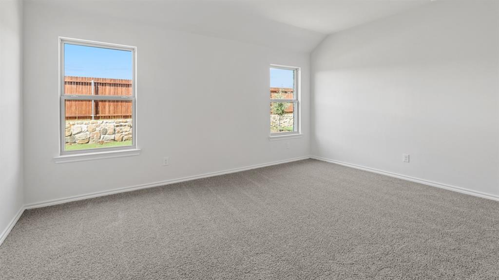 1923 Reveille Way Terrell, TX 75160 - Photo 19 of 33 Spacious room with plush gray carpeting, crisp white walls, and a vaulted ceiling