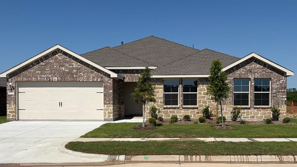 1923 Reveille Way Terrell, TX 75160 - Photo 31 of 33 Brick and stone veneer exterior featuring a two-car garage with carriage-style doors, dark framed windows, and a shingled roof