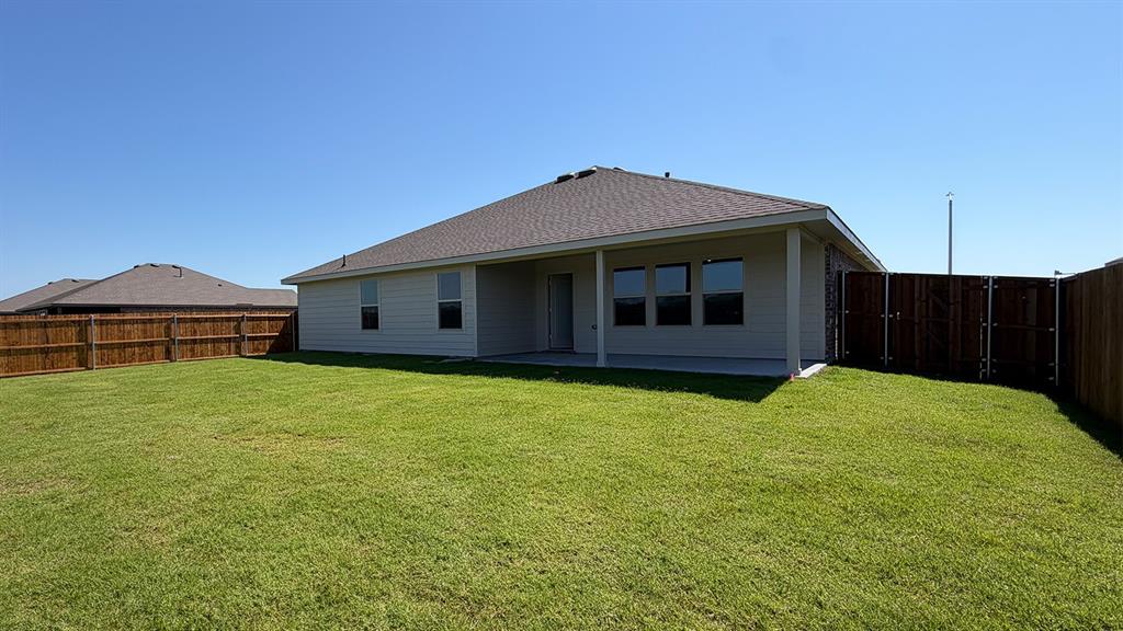 1923 Reveille Way Terrell, TX 75160 - Photo 33 of 33 Expansive fenced backyard featuring a covered patio, neutral-toned siding, a dark shingle roof, and multiple windows