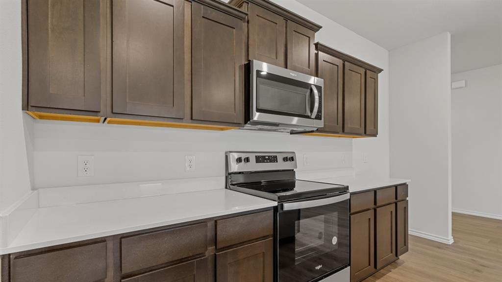 1923 Reveille Way Terrell, TX 75160 - Photo 10 of 33 Contemporary kitchen featuring dark wood-finish cabinetry, white solid-surface countertops, and a subway tile backsplash