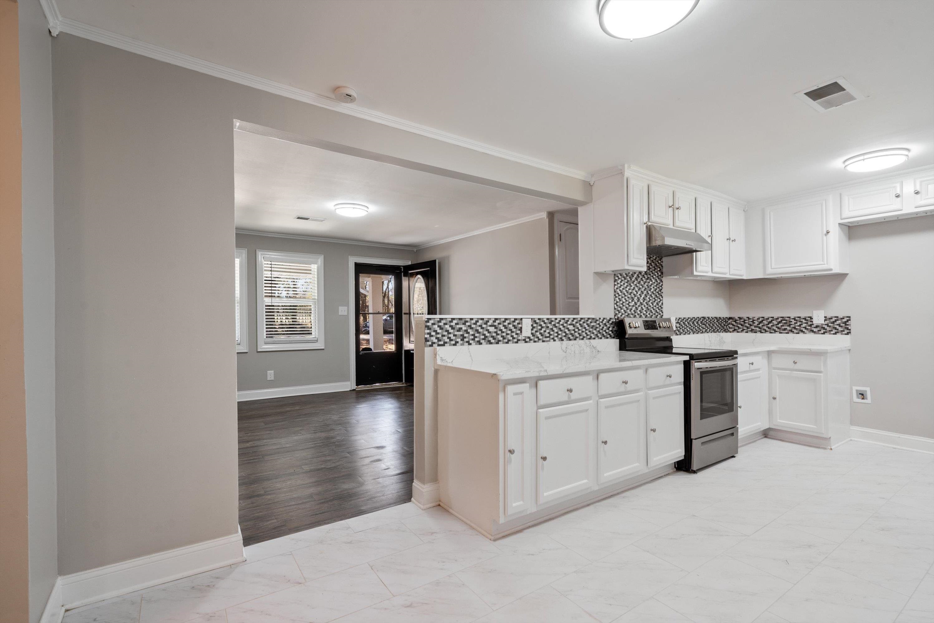 10464 East Holmes Road Collierville, TN 38017 - Photo 2 of 12 Kitchen with electric range, light marble finish floors, white cabinetry, ornamental molding, and under cabinet range hood