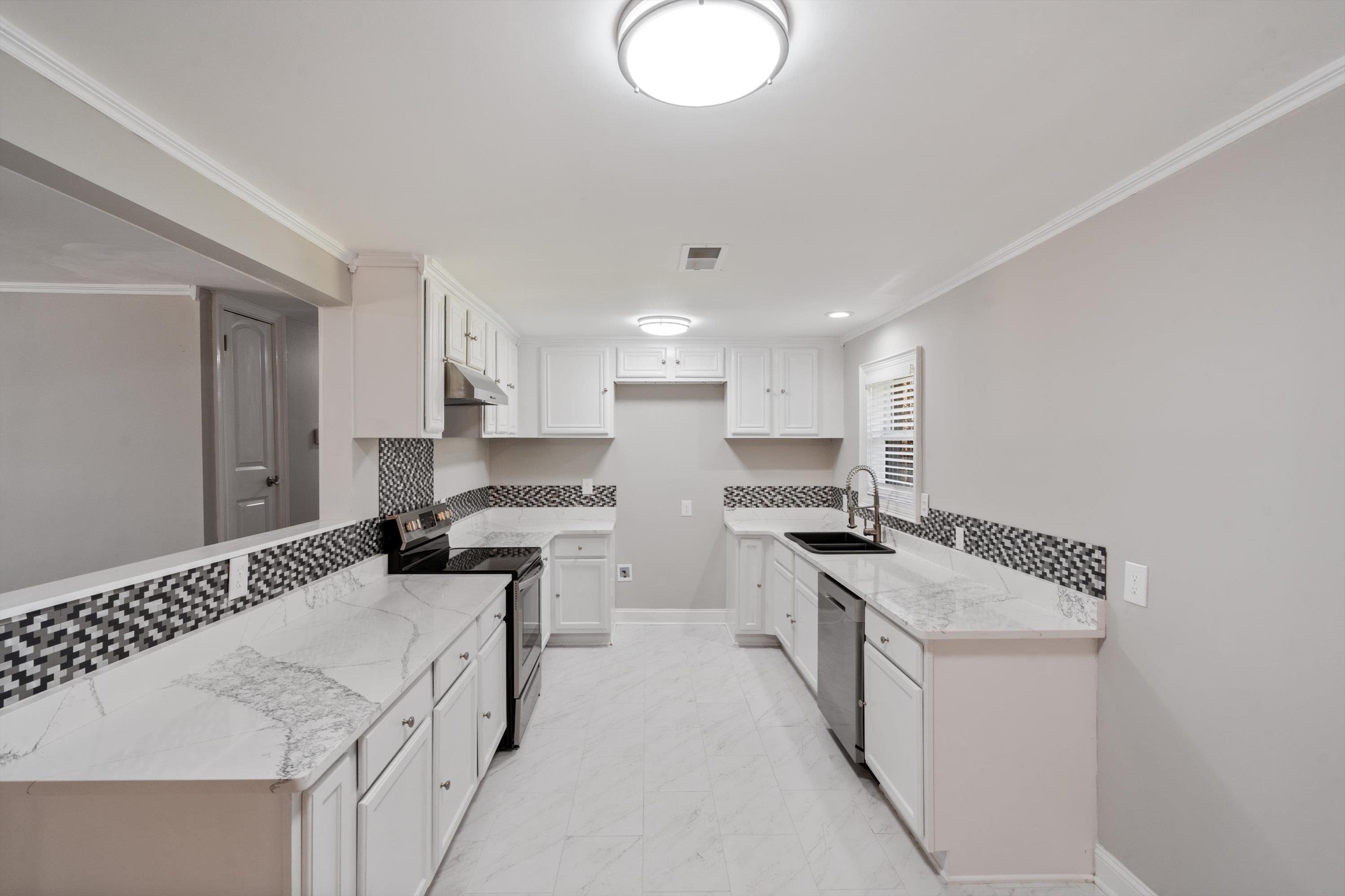 10464 East Holmes Road Collierville, TN 38017 - Photo 3 of 12 Kitchen featuring appliances with stainless steel finishes, light stone countertops, tasteful backsplash, white cabinetry, and crown molding