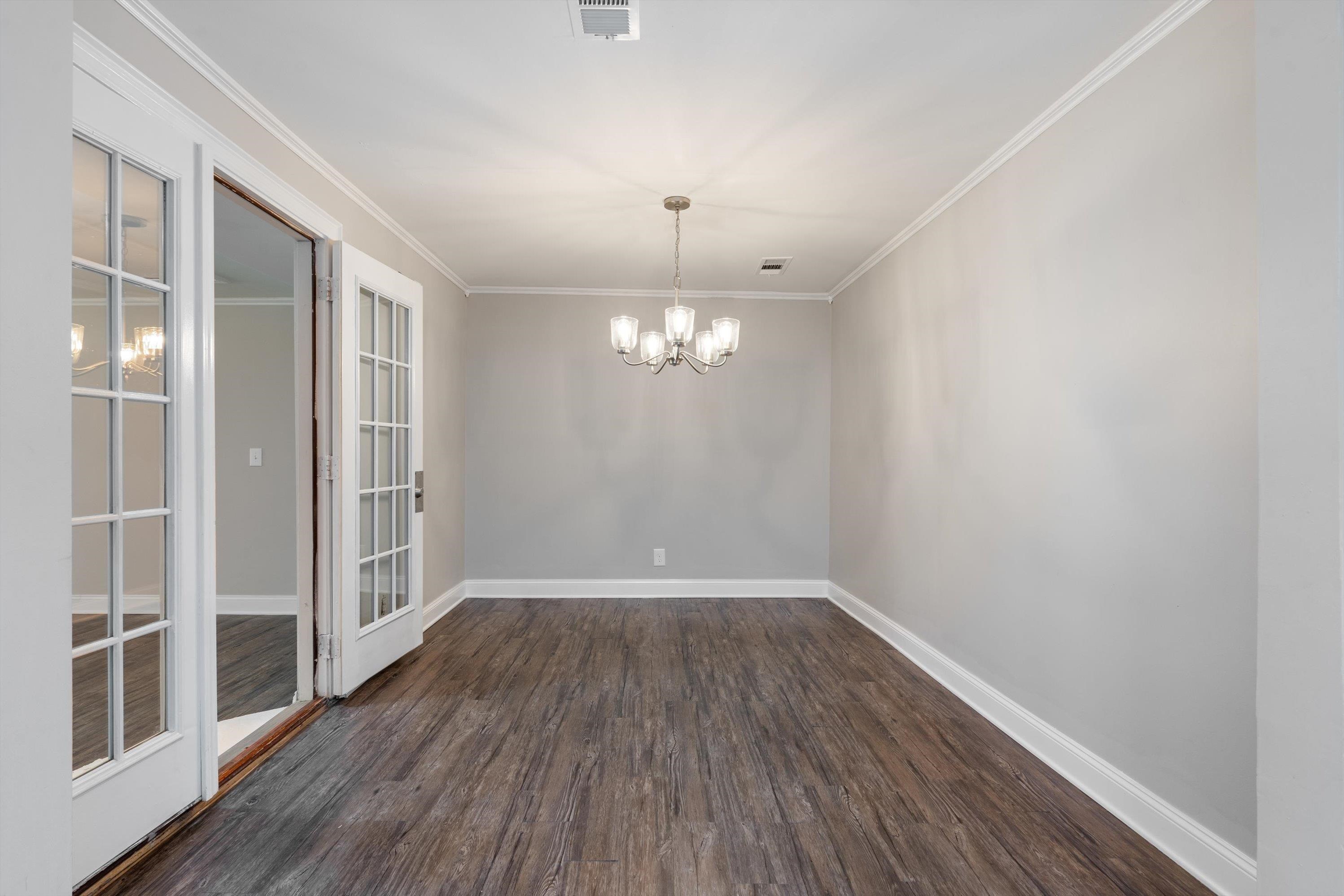 10464 East Holmes Road Collierville, TN 38017 - Photo 4 of 12 Unfurnished room with a chandelier, dark wood-type flooring, crown molding, and french doors