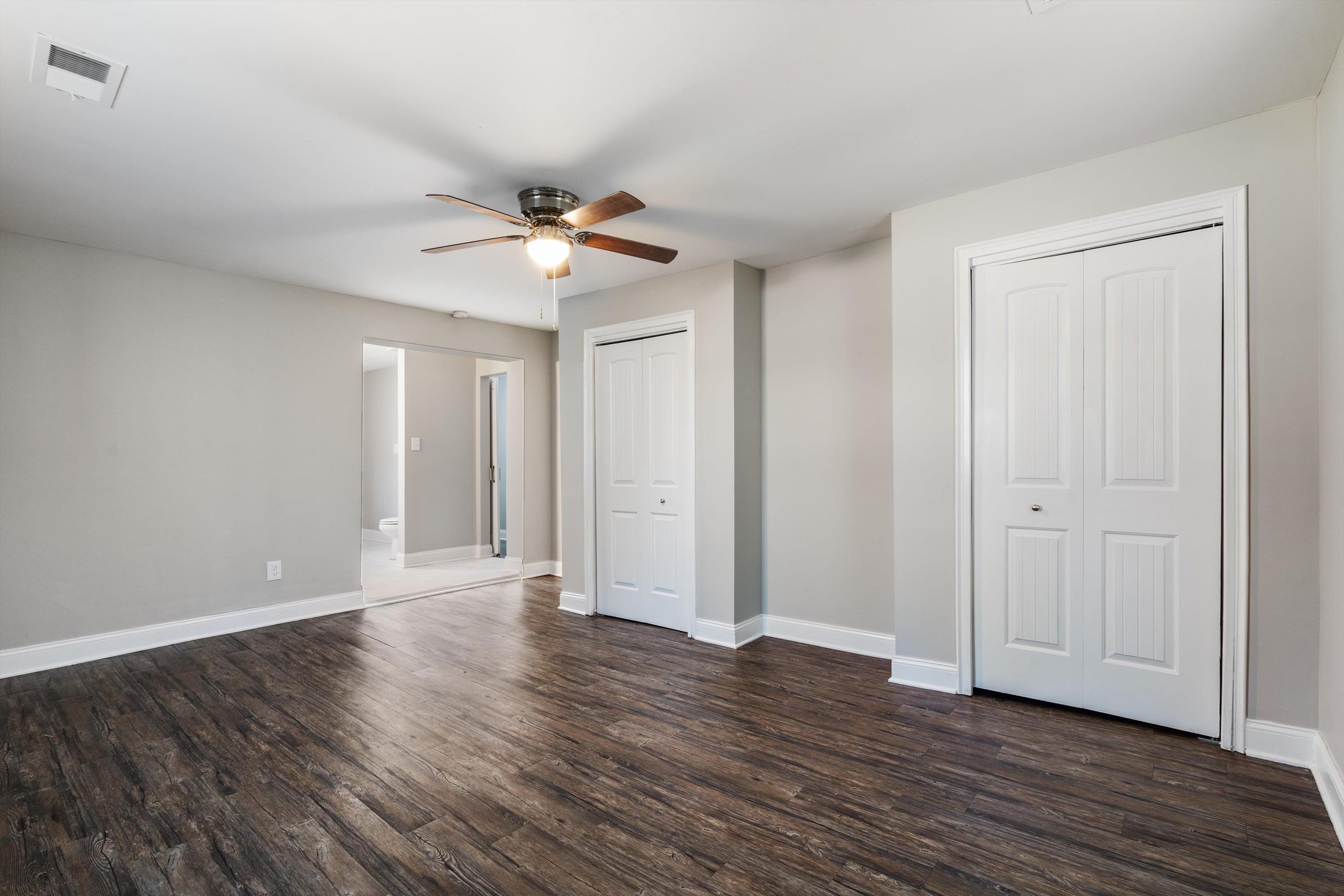 10464 East Holmes Road Collierville, TN 38017 - Photo 7 of 12 Unfurnished bedroom with multiple closets, dark wood-type flooring, and ceiling fan
