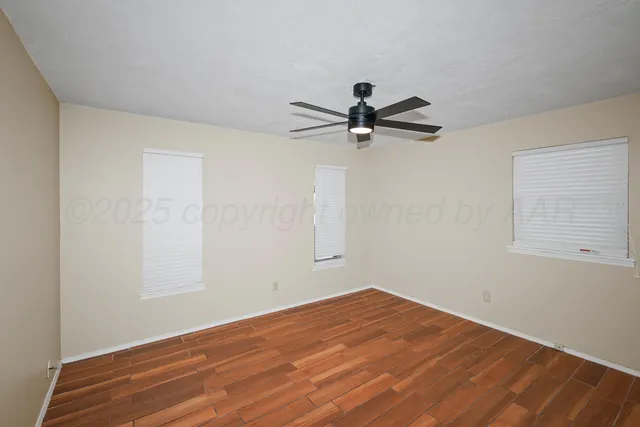 a view of a room with wooden floor and a ceiling fan