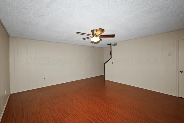 a view of empty room with wooden floor and door