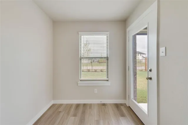 a view of an empty room with wooden floor and a window
