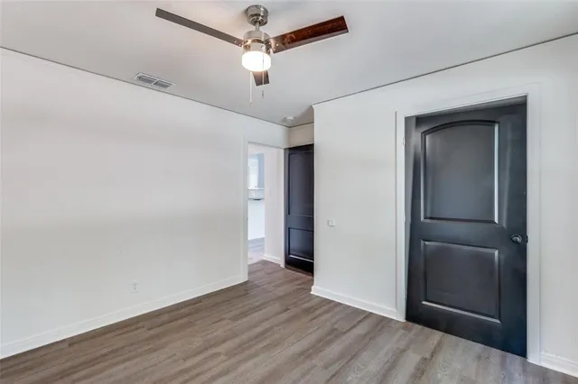 an empty room with wooden floor closet and windows