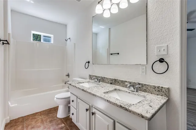 a bathroom with a granite countertop sink a toilet and bathtub