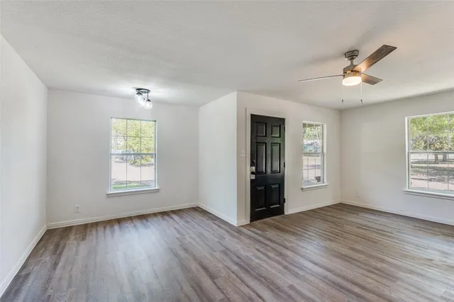 a view of an empty room with a window and wooden floor