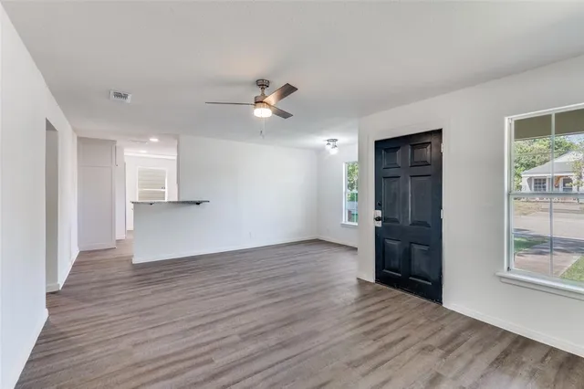 a view of an empty room with window and wooden floor