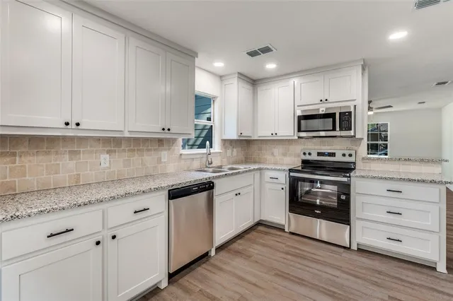 a kitchen with granite countertop white cabinets and stainless steel appliances