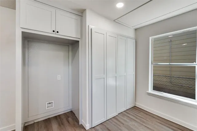 a view of an empty room with wooden floor and closet