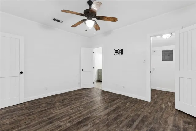 an empty room with wooden floor fan and windows