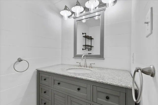 a bathroom with a granite countertop sink a mirror and vanity
