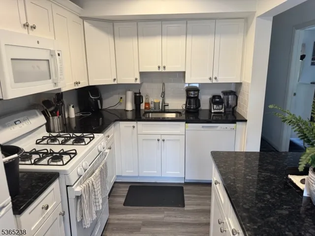a kitchen with stainless steel appliances granite countertop a stove a sink and a white cabinets
