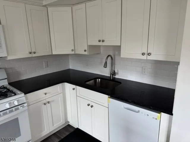 a kitchen with white cabinets and sink