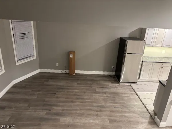 a view of a refrigerator in kitchen and an empty room