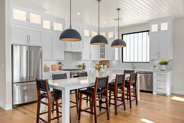 a kitchen with stainless steel appliances a dining table chairs stove and refrigerator