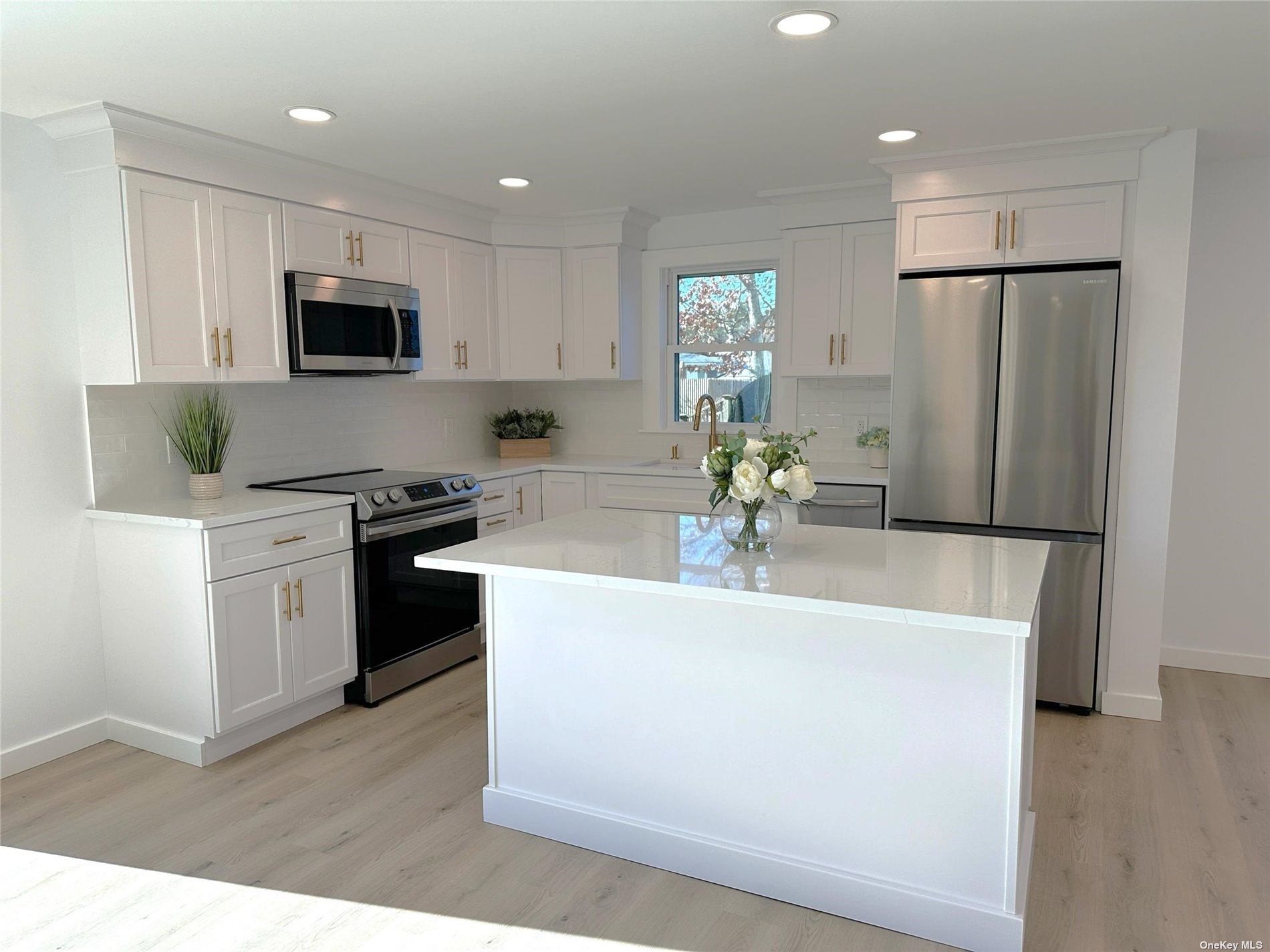 a kitchen with stainless steel appliances a refrigerator a sink a stove a microwave a counter top space and cabinets