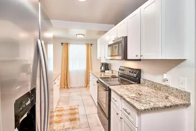 a kitchen with granite countertop a sink a stove top oven and cabinetry