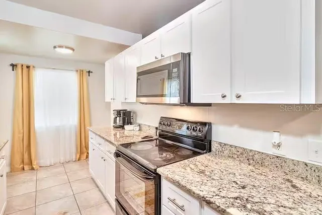 a kitchen with kitchen island granite countertop a sink stove and cabinets