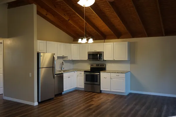 a kitchen with a refrigerator a stove top oven a sink and dishwasher with wooden floor