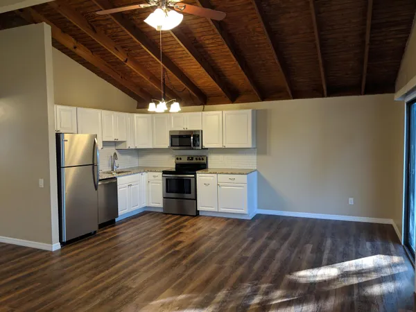 a kitchen with granite countertop a refrigerator and a stove top oven