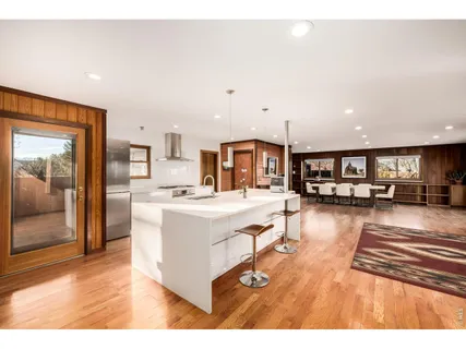 a living room with stainless steel appliances kitchen island granite countertop a sink and a refrigerator