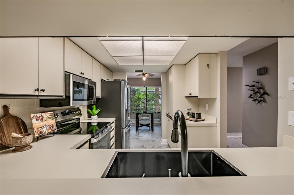 1801 East Lake Road South, Unit 6D Palm Harbor, FL 34685 - Photo 2 of 24 a kitchen with stainless steel appliances granite countertop a sink a stove and a wooden cabinets