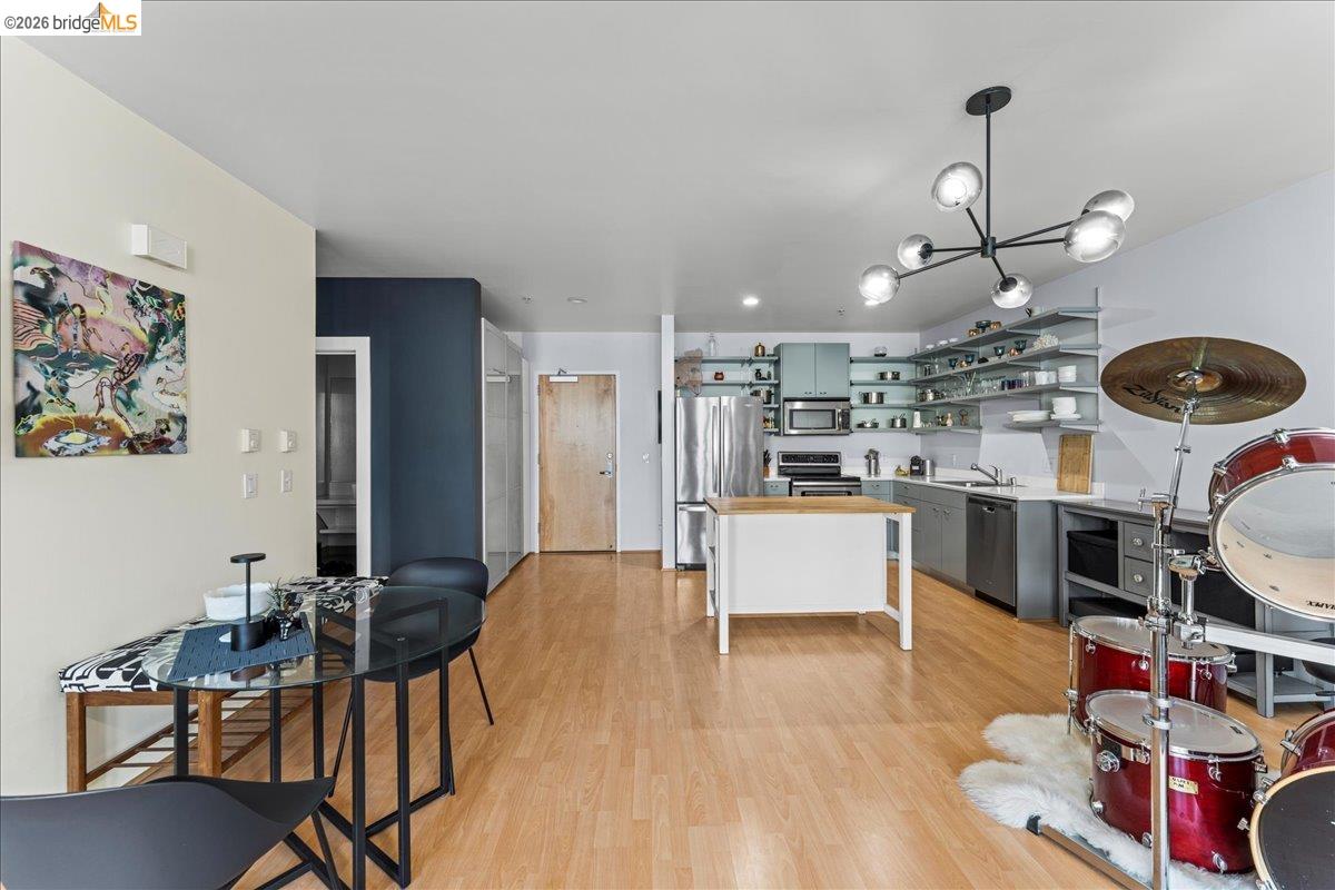 1201 Pine Street, Unit 354 Oakland, CA 94607 - Photo 22 of 26 a kitchen with stainless steel appliances granite countertop a stove a refrigerator and a dining table with wooden floor