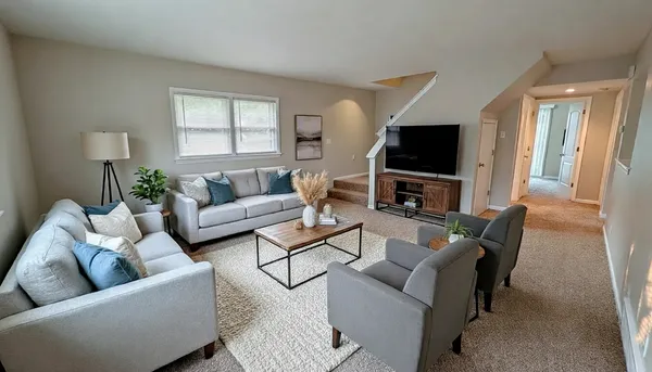 a living room with furniture a flat screen tv and a window