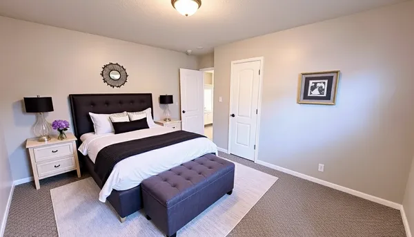 a spacious bedroom with a bed and a lamp on table
