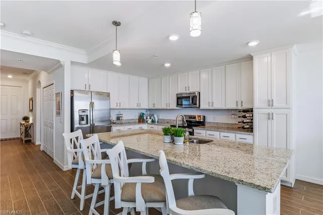 a kitchen with stainless steel appliances granite countertop a stove refrigerator and white cabinets with wooden floor