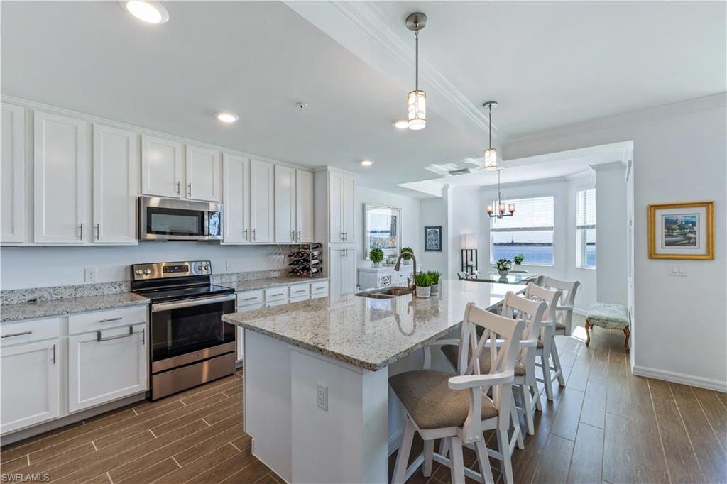43010 Greenway Boulevard, Unit 237 Punta Gorda, FL 33982 - Photo 5 of 11 a kitchen with stainless steel appliances granite countertop a stove top oven a sink dishwasher a dining table and chairs with wooden floor
