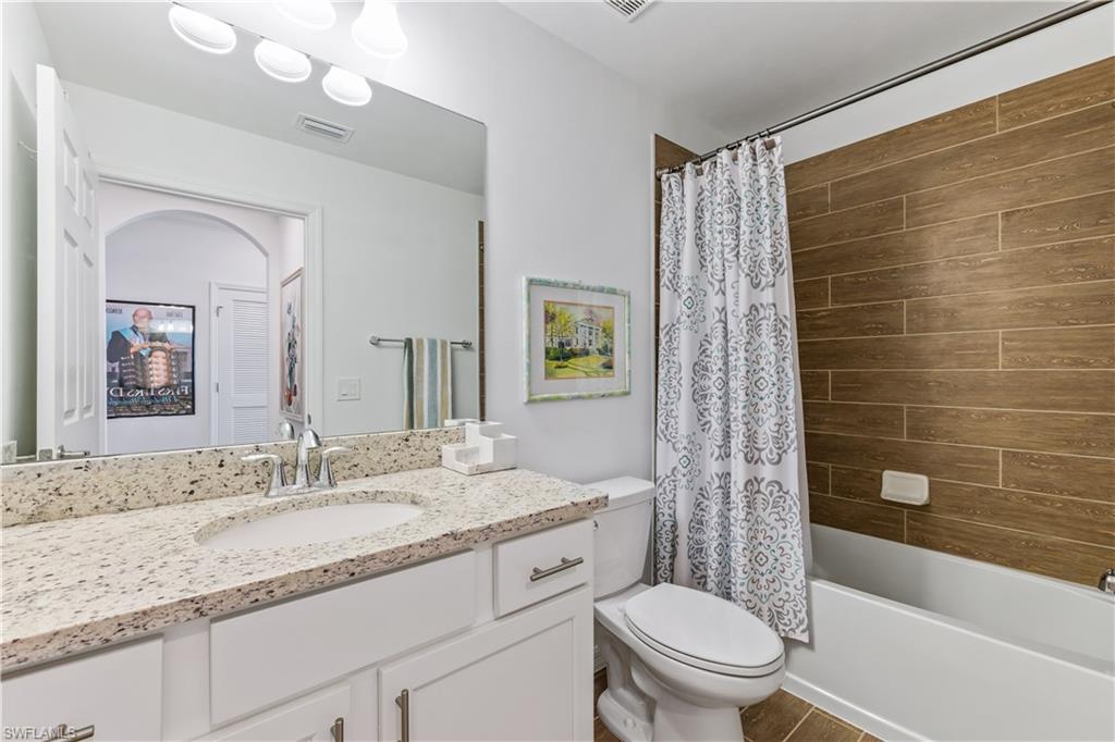 43010 Greenway Boulevard, Unit 237 Punta Gorda, FL 33982 - Photo 9 of 11 a bathroom with a granite countertop sink a toilet a mirror a bathtub and shower