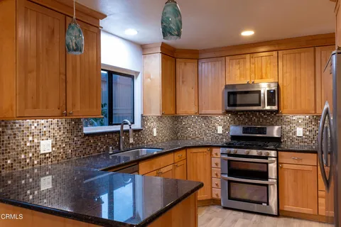 a kitchen with stainless steel appliances granite countertop a stove a sink and a microwave