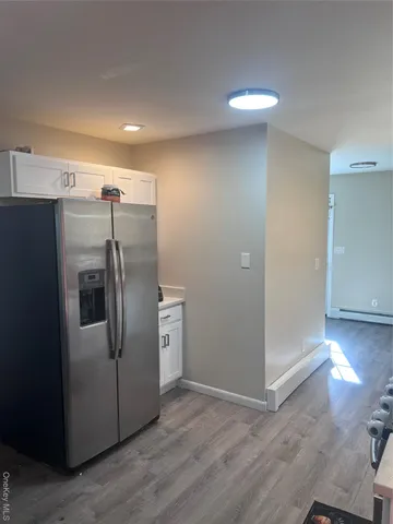 a view of a refrigerator in kitchen and an empty room