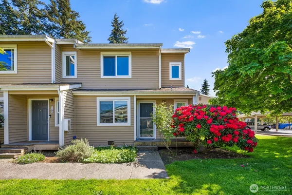 a front view of house and yard with beautiful flowers and green space